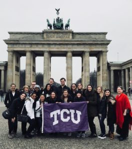 A group of Communication Studies majors pose with the TCU flag on their study abroad trip.