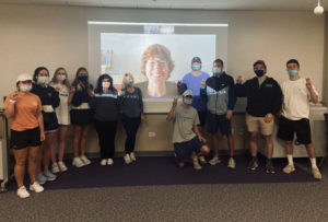 Students in Instructor Moore’s class pose in front of a screen with expert tour guide Vicky Bailey smiling via a Zoom meeting.