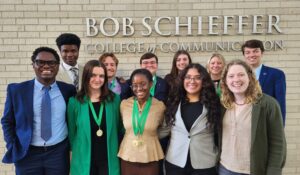 Members of the TCU Speech and Debate Team 2025-2026 standing together in front of the Bob Schieffer College of Communication building.