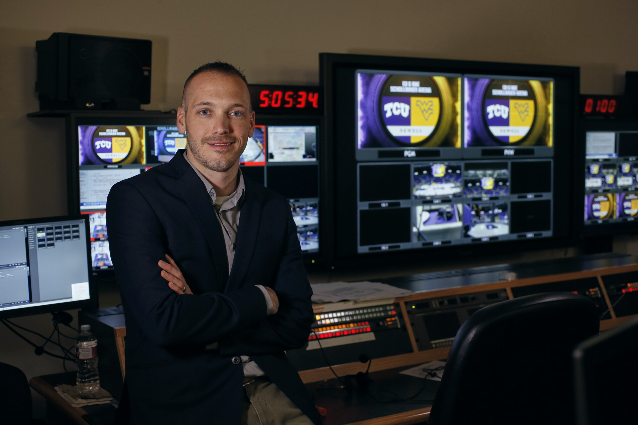 Associate Professor Dustin Hahn leans against a broadcasting console, facing the camera.