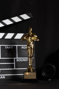 Image of a golden trophy with a clapboard and camera in the background.