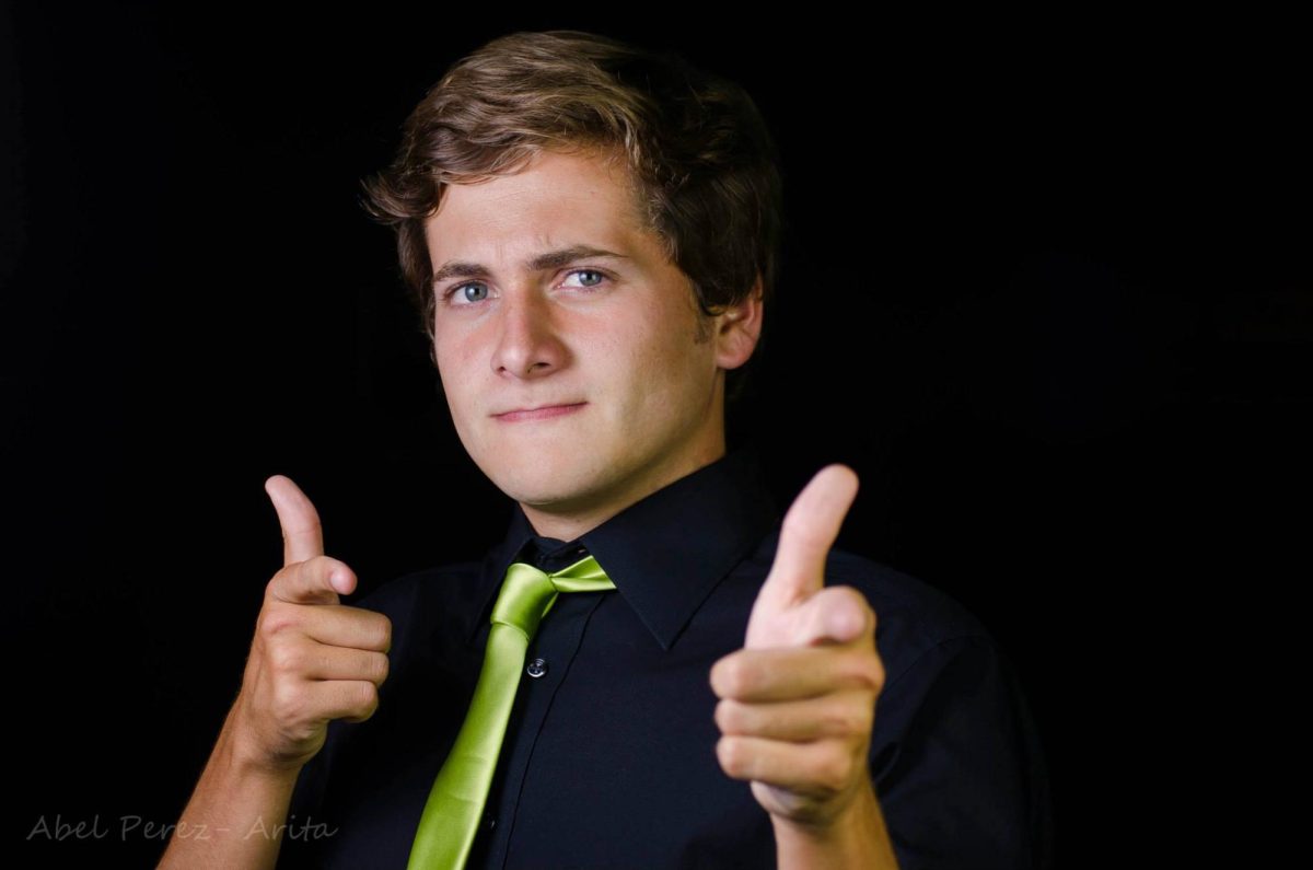 A portrait of a young man shooting finger guns at the camera.