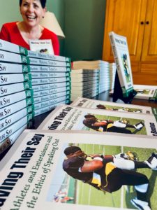 A photo of Schieffer College dean Kristie Bunton with stacks of her new book, "Having Their Say: Athletes and Entertainers and the Ethics of Speaking Out."