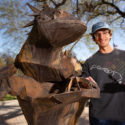 TCU student JD Pells poses next to a Horned Frog statue on campus.