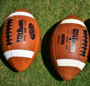Two footballs photographed side by side on the field at Amon Carter Stadium on the TCU campus in Fort Worth, Texas. Photo by Michael Clements