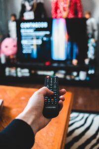 Hand holding a remote in front of a tv