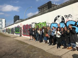 A group of Communication Studies students pose in front of a graffiti wall on their study abroad trip.